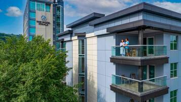 A hotel with a modern design, featuring multiple balconies with glass railings and outdoor seating.