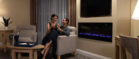 A modern living room with a flat-screen TV, a fireplace, and a dining area with a table and chairs.