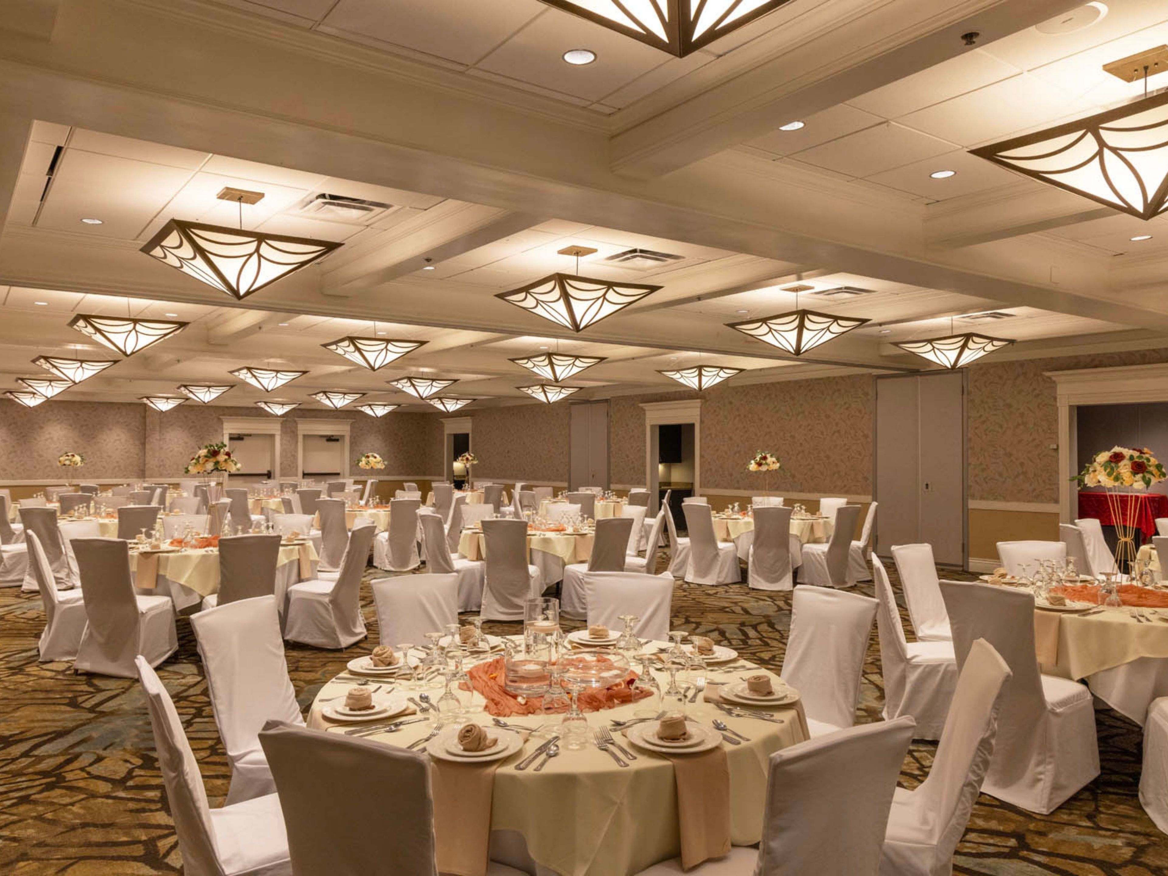 Un salón de banquetes con mesas redondas, manteles blancos y sillas.