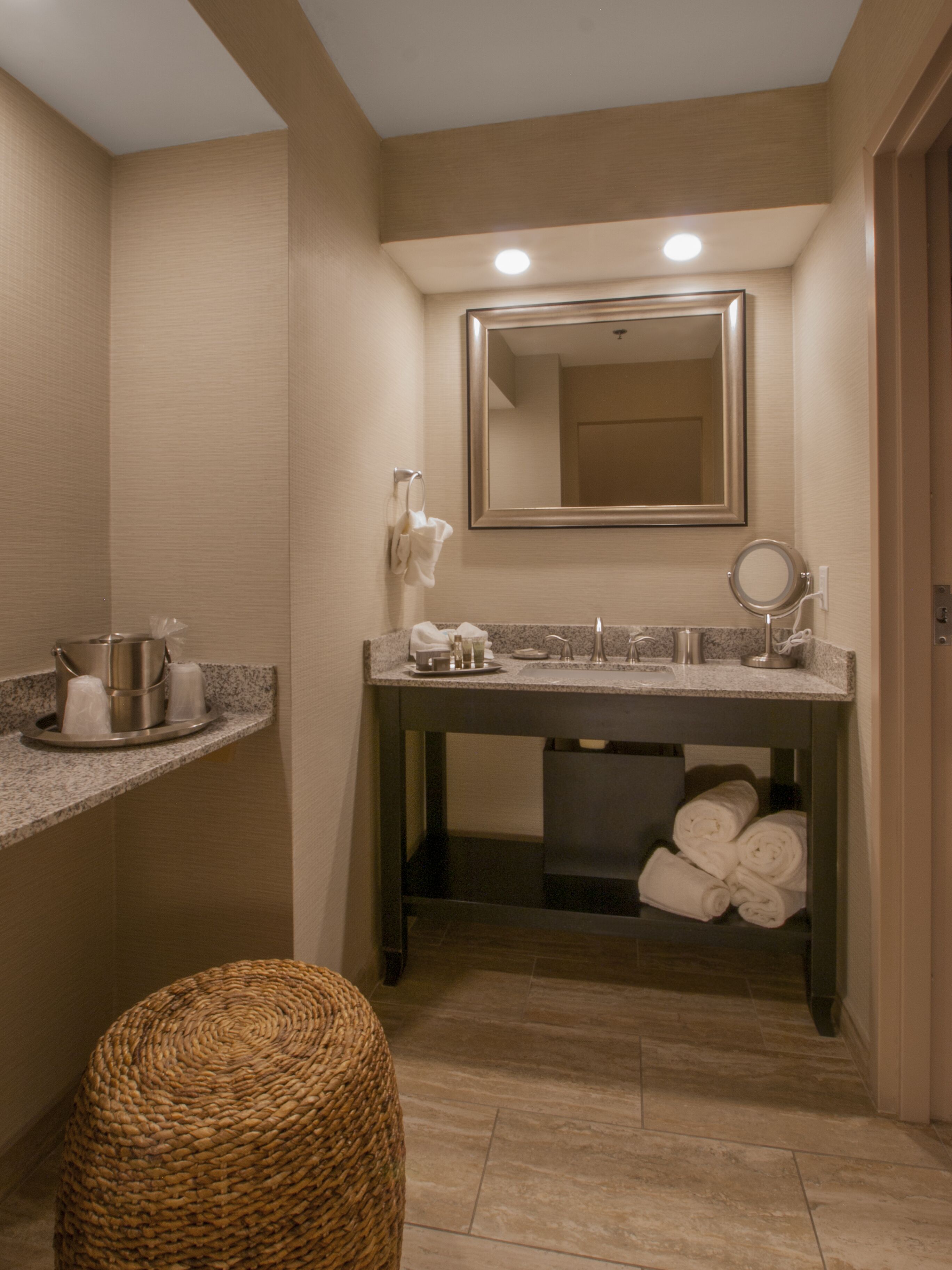 Une salle de bain avec un comptoir en granit, un lavabo avec un miroir et un porte-serviettes.