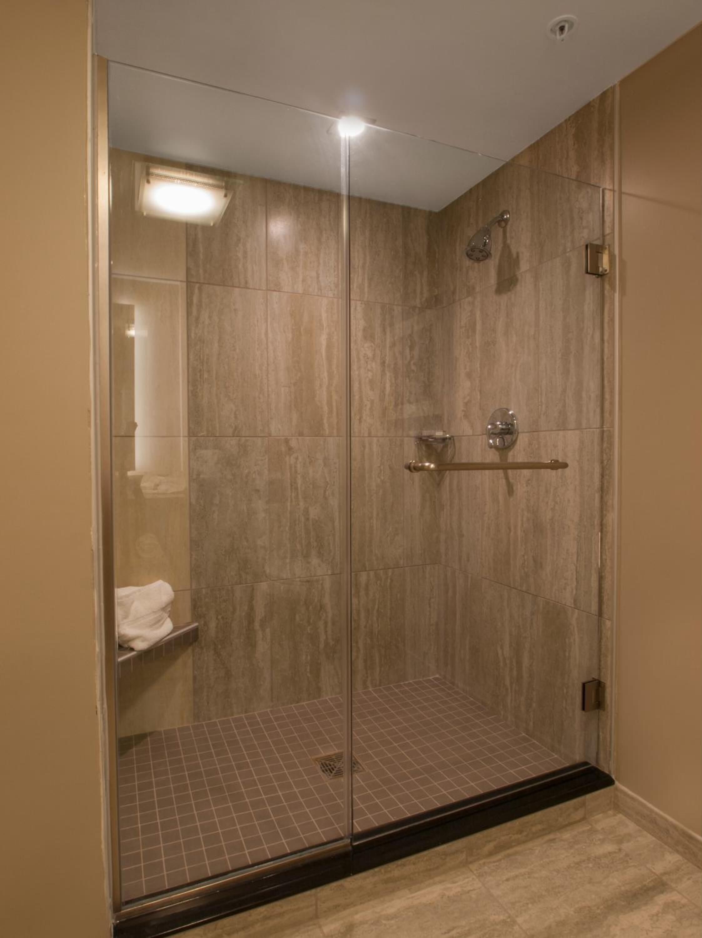 A walk-in shower with a glass door, a towel rack, and a ceiling light.