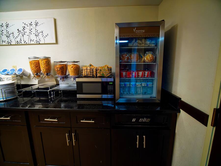 Ein Frühstücksbuffet mit Kaffeeautomat, Kühlschrank voller Getränke und einer Speisenauslage.