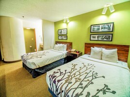 A hotel room with two beds, a nightstand with a phone, and framed pictures on the wall.