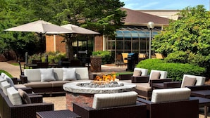 An outdoor seating area with wicker furniture, a stone fire pit, and umbrellas.