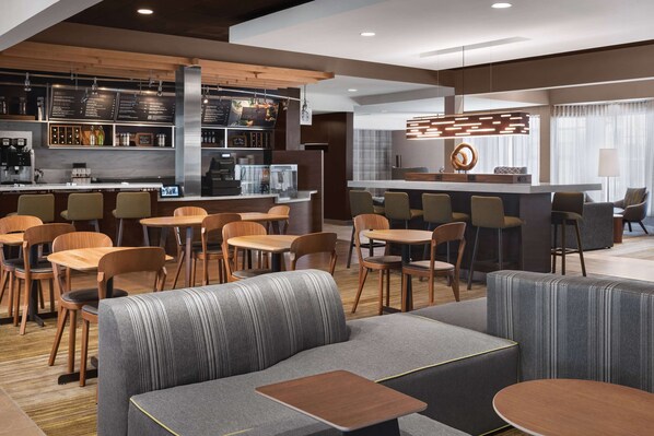 A modern cafe with a bar area, seating arrangements, and a counter with menu boards. - Sonesta Select Newport Middletown (Middletown)