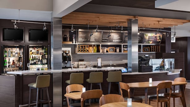 A modern bar area with a counter, seating, and various bottles and glasses.