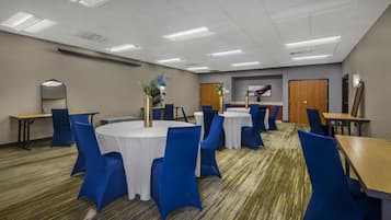 A conference room with round tables, blue chairs, and a carpeted floor.