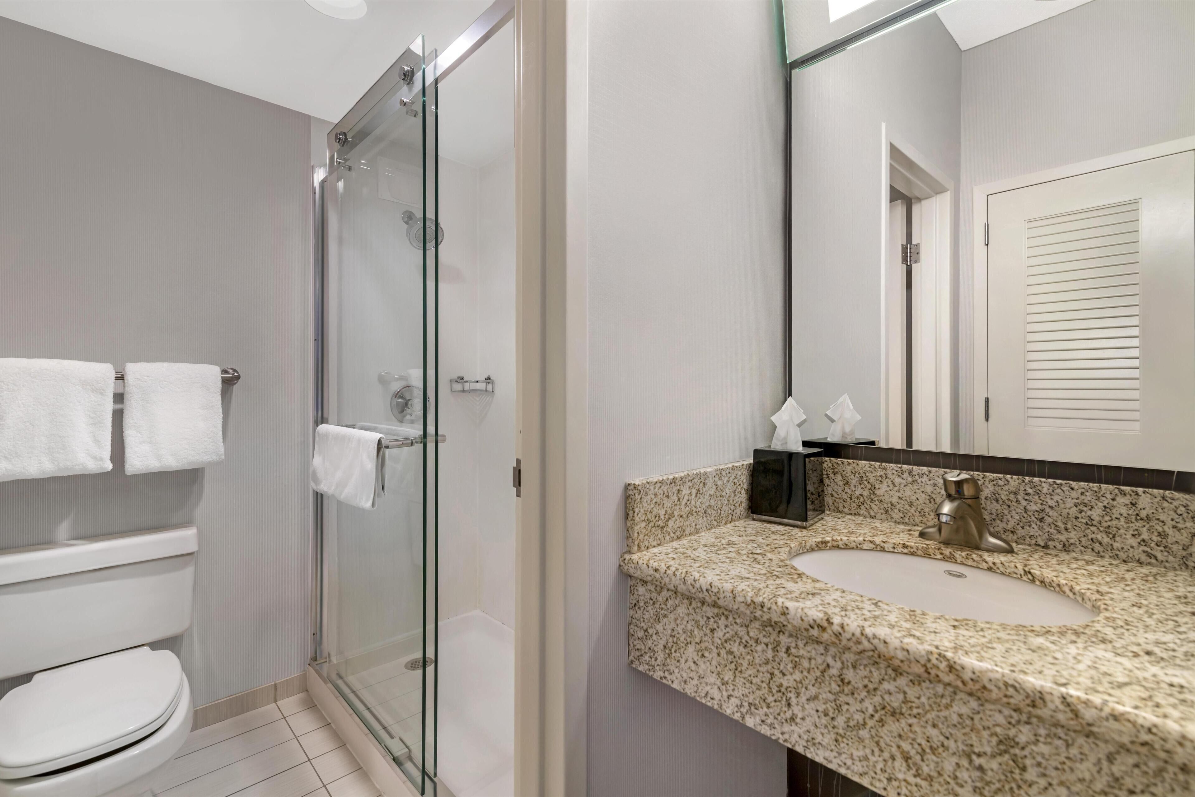 Une salle de bain moderne avec une douche à parois de verre, des toilettes et un lavabo doté d’un plan de travail en marbre.