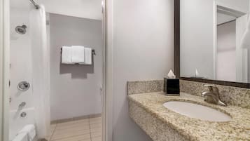 Un baño moderno con lavamanos de granito, un espejo y zona de ducha.