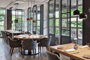 A modern dining area with a round table set for six, surrounded by grey upholstered chairs. - Courtyard by Marriott Wiesbaden-Nordenstadt (Wiesbaden)