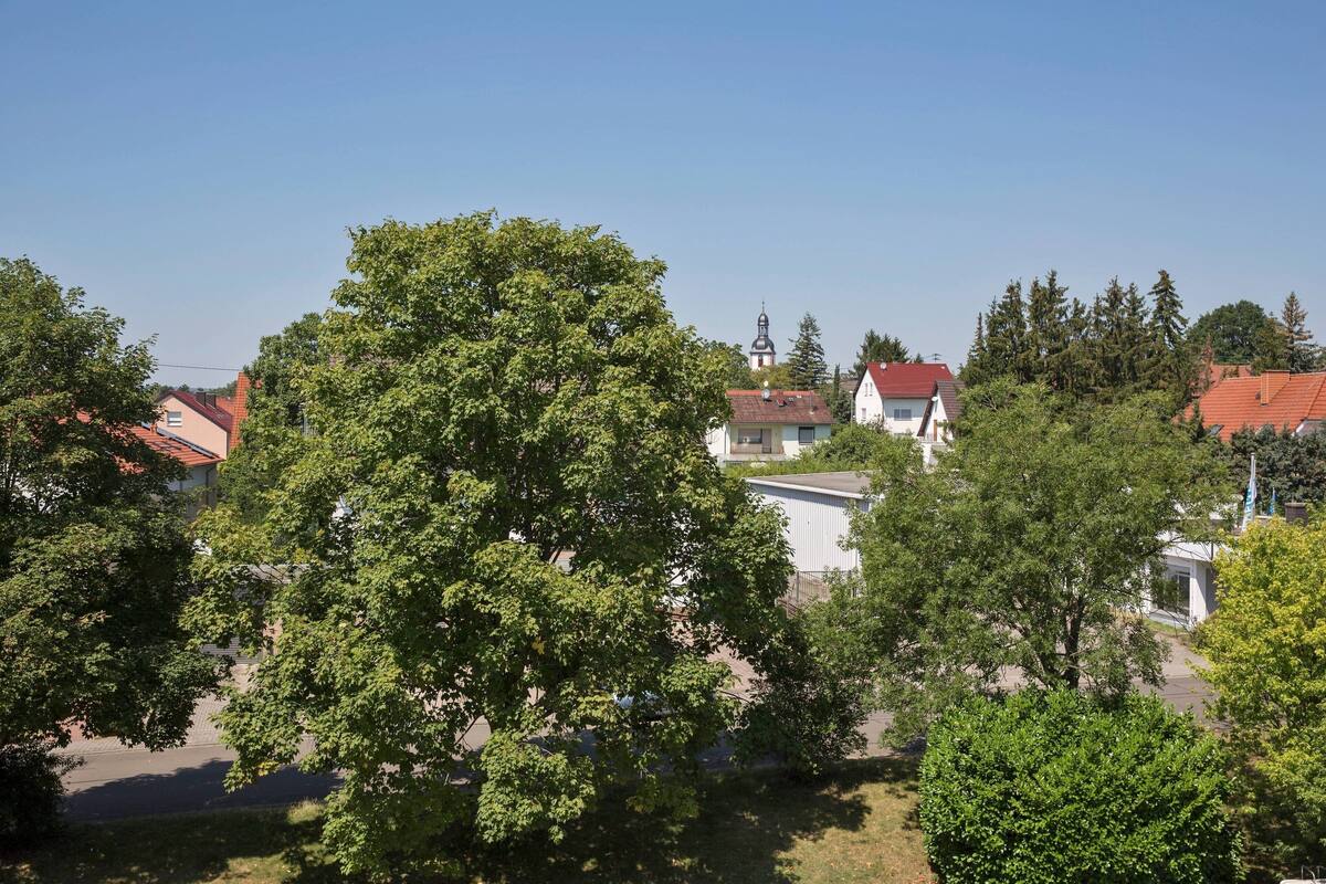 Ein Wohngebiet mit Häusern, Bäumen und einem Kirchturm.