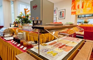 A buffet setup with various food items and beverages, a coffee machine, and a decorative plant. - Hotel Boltzmann (Vienna)