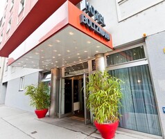 The exterior of Hotel Boltzmann with a modern design, featuring a glass entrance and red potted plants.