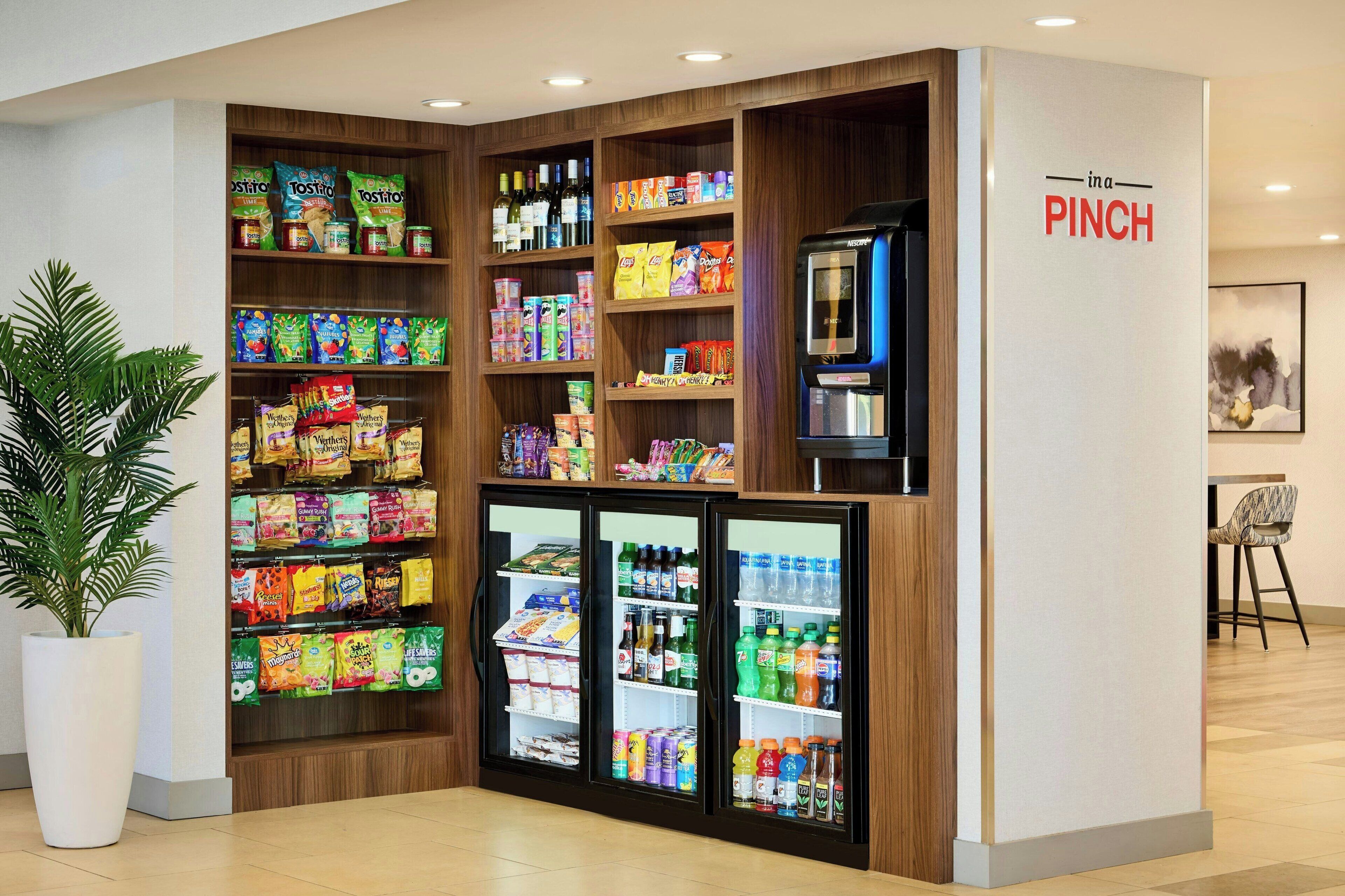Quiosco de aperitivos y bebidas con refrigerador y estantes llenos de diversos productos.
