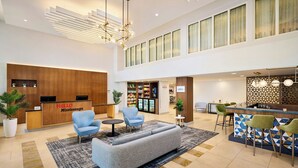A modern hotel lobby with a reception desk, seating area, and a bar. - TownePlace Suites by Marriott Mississauga-Arpt Corp Ctr (Mississauga)