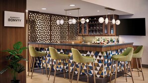 A bar area with a counter, stools, and a TV mounted on the wall. - TownePlace Suites by Marriott Mississauga-Arpt Corp Ctr (Mississauga)