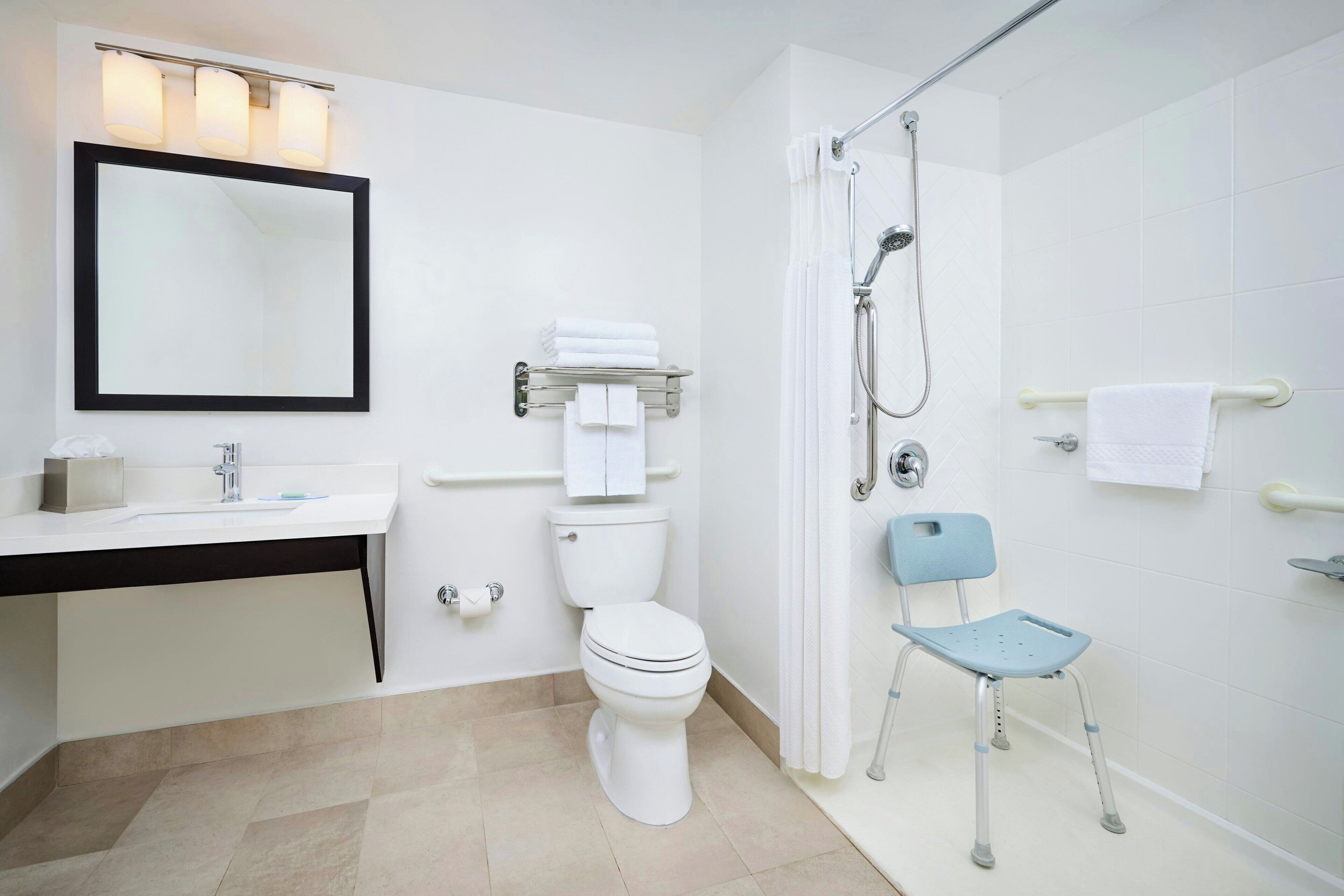 Un baño moderno con lavamanos, inodoro y zona de ducha blancos.