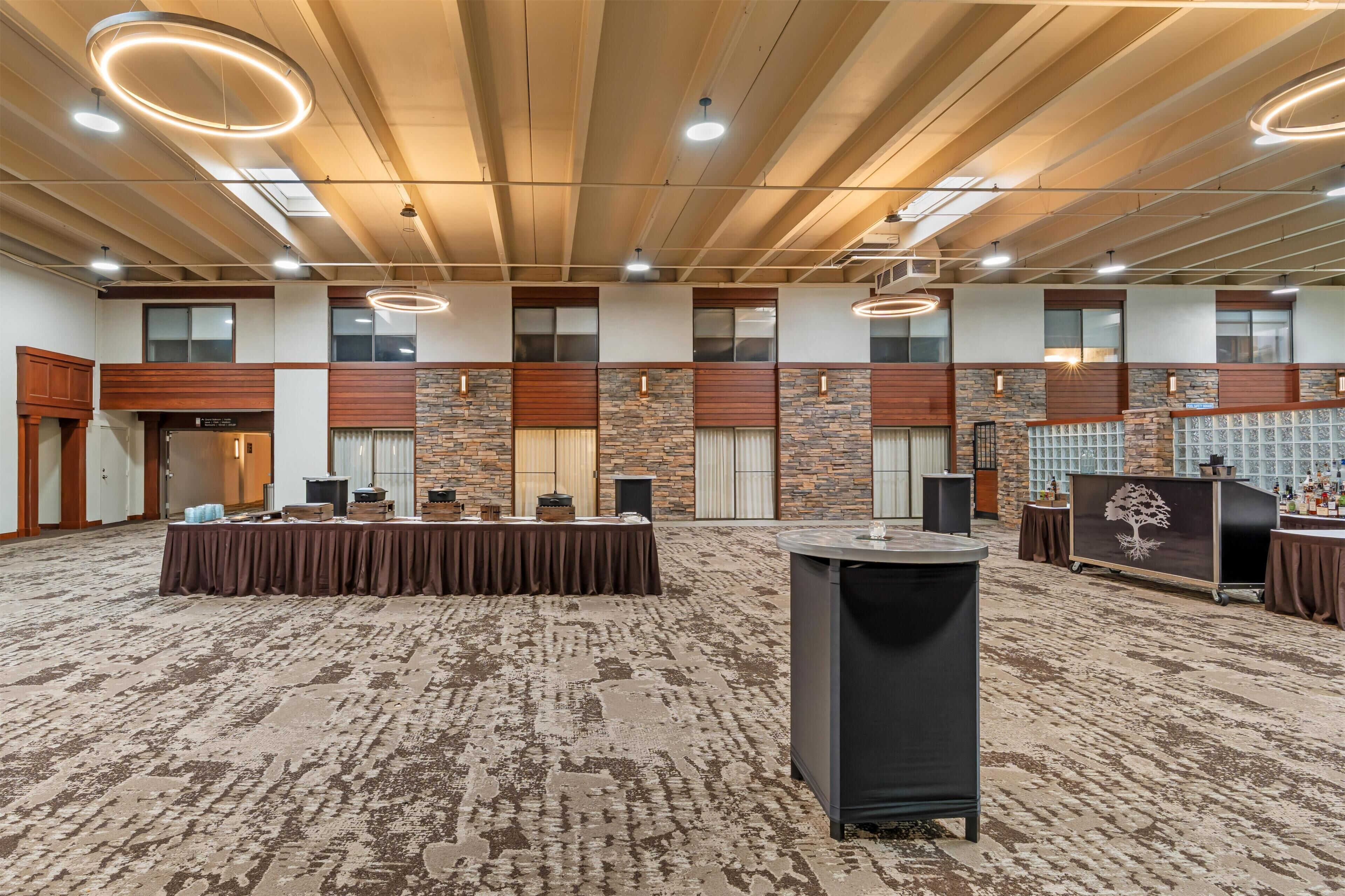 A spacious conference room with a long table, multiple windows, and a high ceiling with exposed beams.