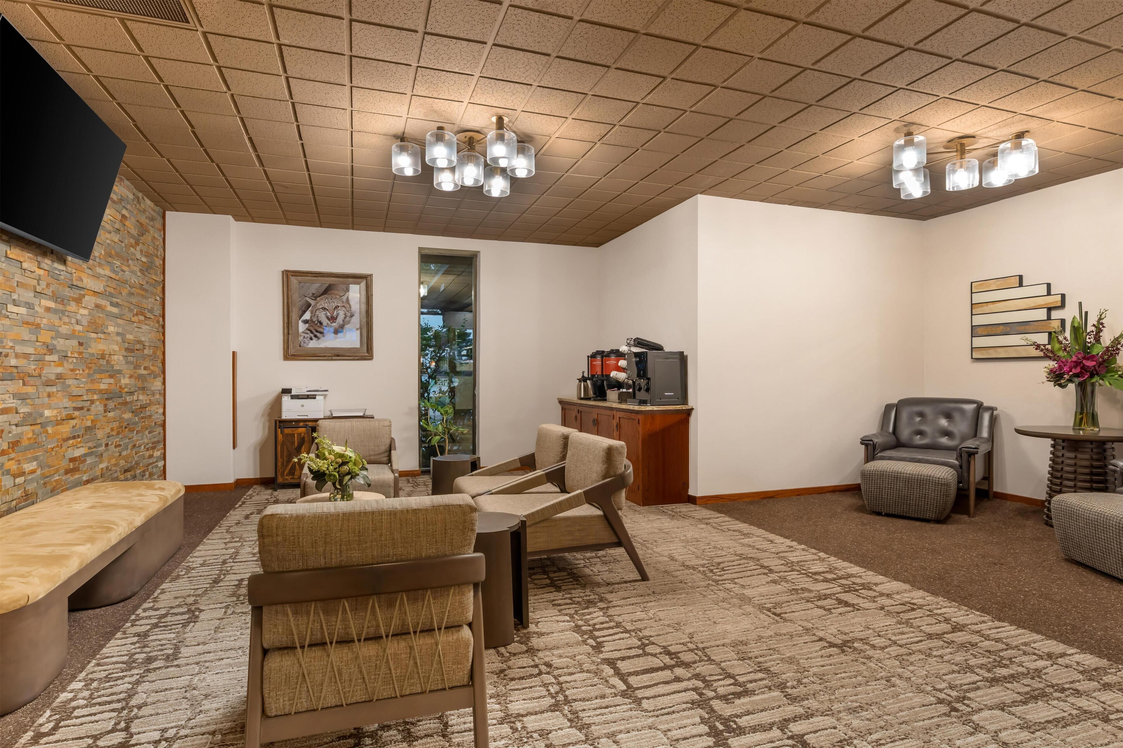 Una sala de estar moderna con una pared de piedra, un televisor de pantalla plana, una chimenea y una zona de estar con un banco y sillas.