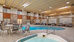 An indoor swimming pool with lounge chairs and a hot tub, surrounded by stone walls and wooden paneling. - Best Western Plus GranTree Inn (Bozeman)