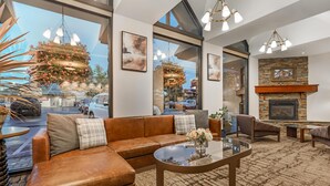 A spacious living area with a leather sofa, a glass coffee table, and a fireplace. - Best Western Plus GranTree Inn (Bozeman)