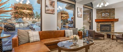 A spacious living area with a leather sofa, a glass coffee table, and a fireplace.