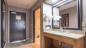 Een hotelbadkamer met een houten wastafel, een grote spiegel en een betegelde vloer.