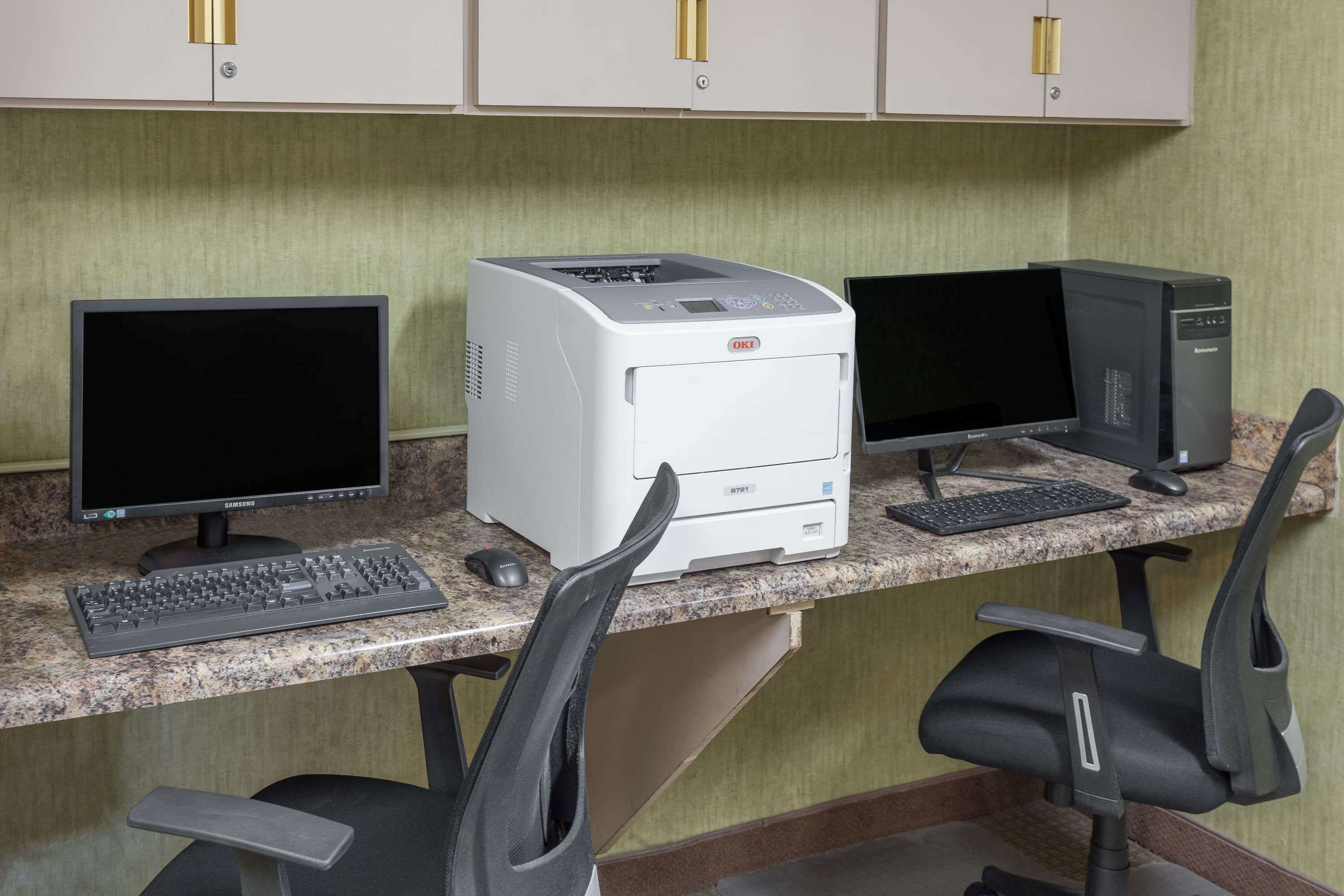 Un poste de travail informatique comprenant un ordinateur de bureau, deux écrans et une imprimante.