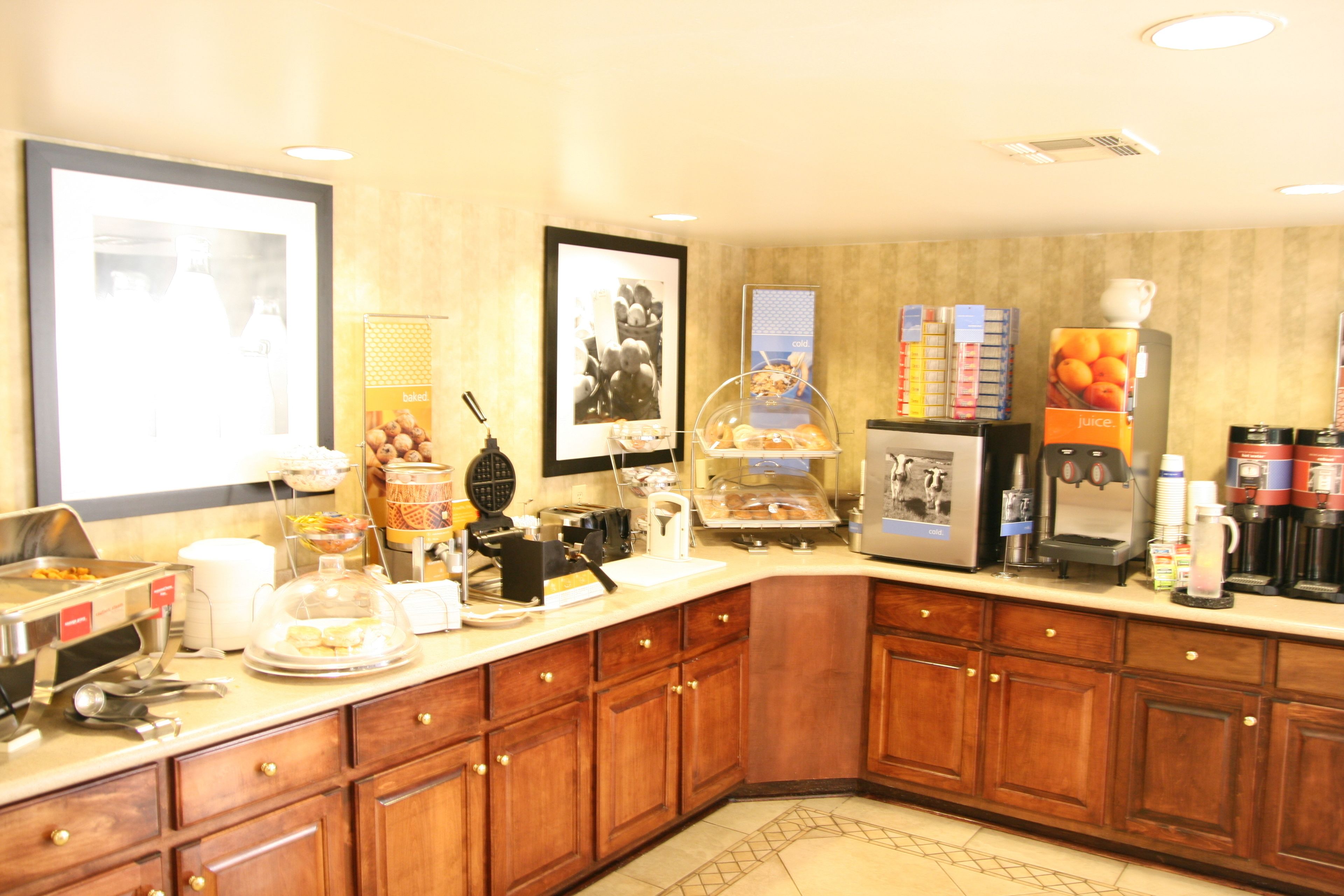 Un comedor de hotel con servicio de buffet, que incluye una estación de café, una exhibición de frutas y diversas opciones de comida.