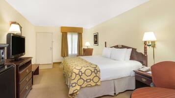 Habitación de hotel con cama, mesita de noche, lámpara, televisión y escritorio con silla.