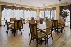 Enjoy meals in this elegant dining area with a high ceiling, large windows, and a potted plant.