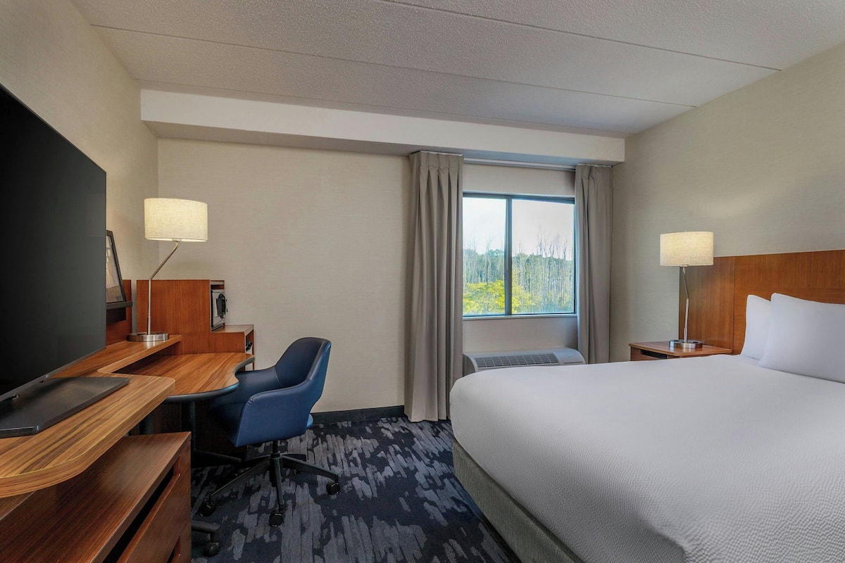 Een hotelkamer met een bed, bureau, stoel en een televisie.