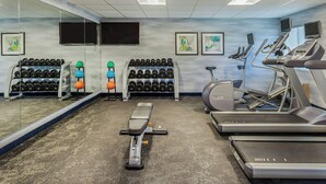 Un gimnasio con cintas de correr, elípticas y una prensa de banca.