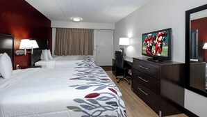 A hotel room with a large bed, a desk, a television, and a mirror.