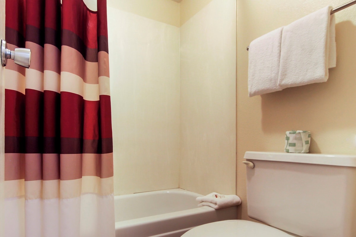 A bathroom with a bathtub, toilet, and a towel rack.