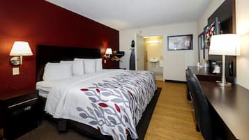Una habitación de hotel con cama, mesitas de noche, escritorio y silla.