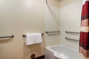 A bathroom with a bathtub, a shower curtain, and handrails. - Red Roof Inn Detroit - Troy (Troy)