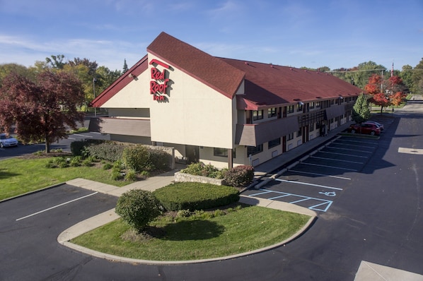 A Red Roof Inn with a parking lot, a covered walkway, and a landscaped area with bushes. - Red Roof Inn Detroit - Troy (Troy)