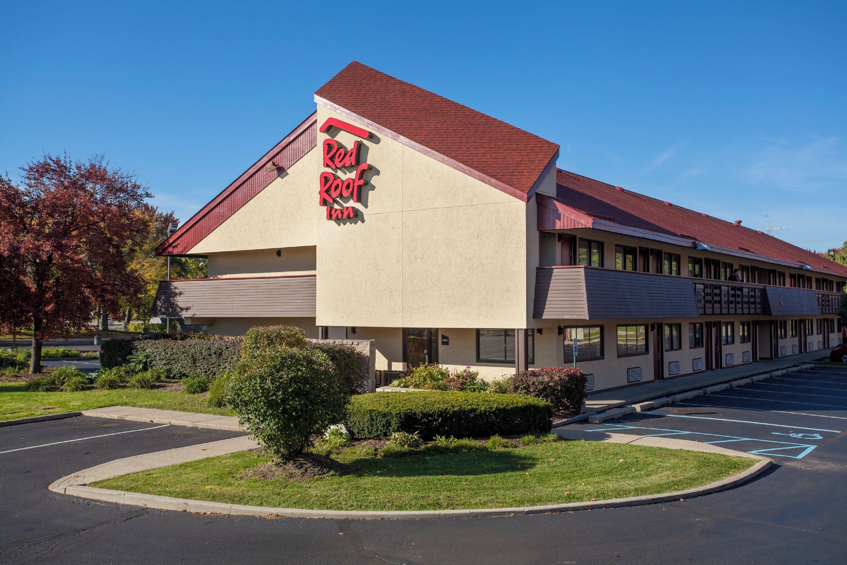 A Red Roof Inn with a red roof, beige exterior walls, and a parking lot with marked spaces.