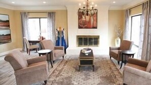 A spacious living room with a chandelier, comfortable seating, a fireplace, and artwork on the walls.