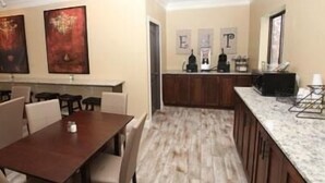 A modern kitchen with a marble countertop, wooden cabinets, and a dining area with a wooden table and chairs.