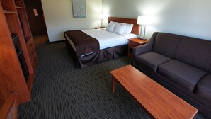 A hotel room with a bed, a sofa, a desk, and a wardrobe.