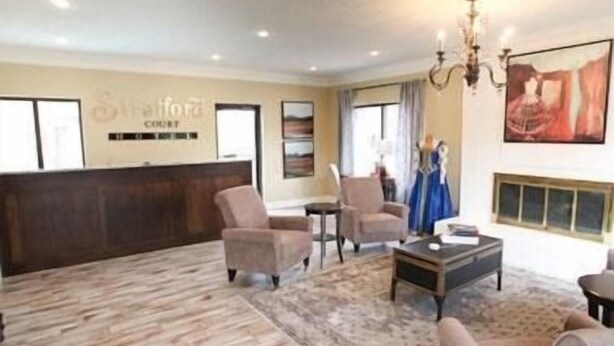 A hotel lobby with a reception desk, several armchairs, a coffee table, and a chandelier.