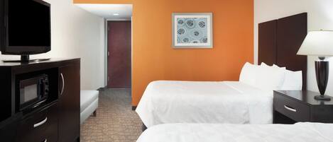 A hotel room with two beds, a TV, a microwave, and a framed picture on the wall.