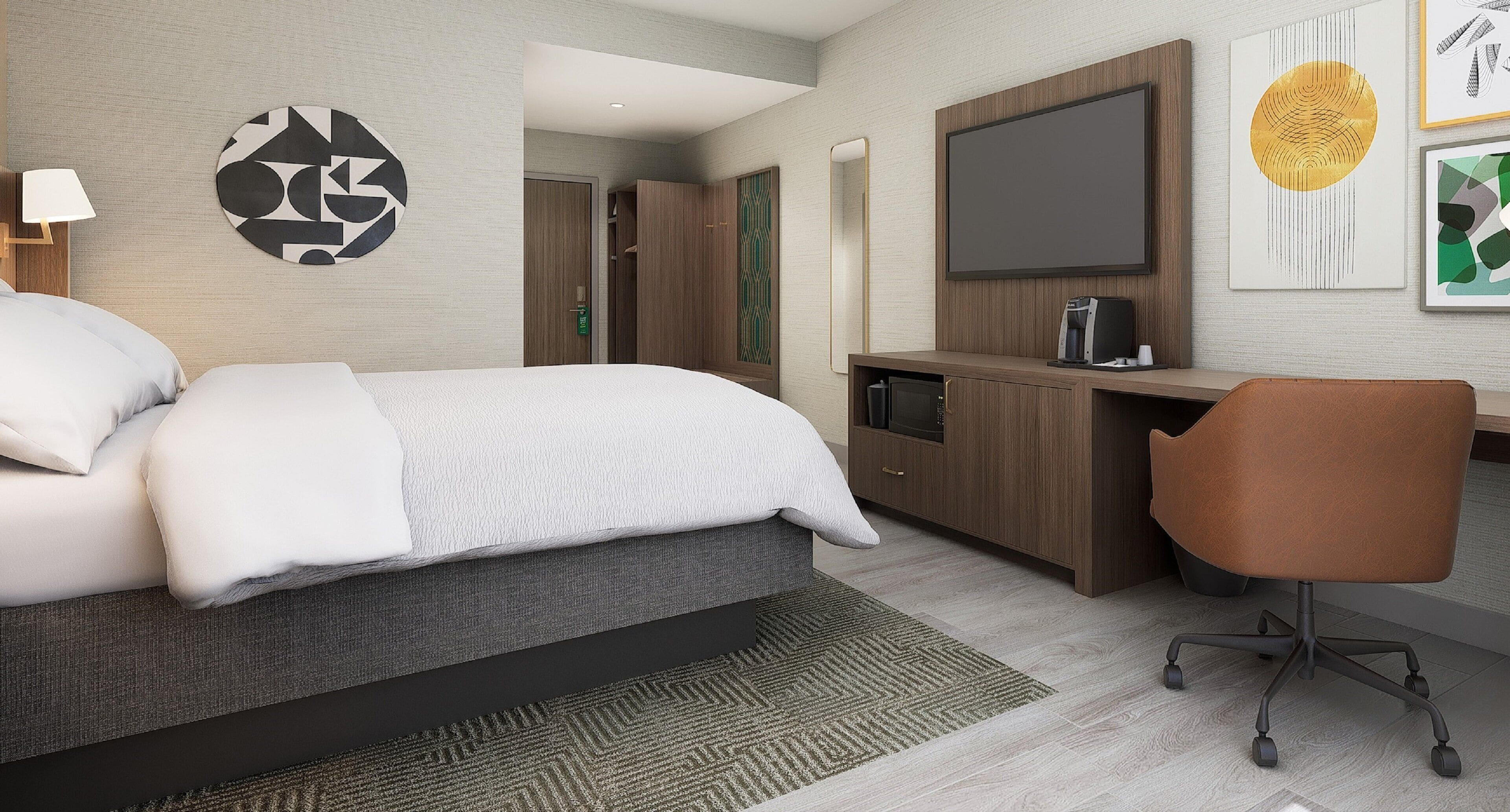 Habitación de hotel con cama, escritorio con silla, televisor y obras de arte en las paredes.