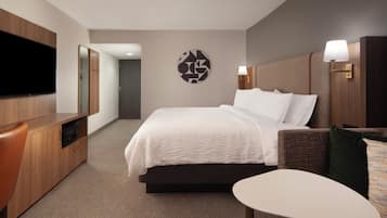 A hotel room with a bed, a TV, a desk, and a chair.