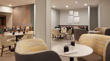 Um hall de hotel moderno, com mesas redondas, assentos confortáveis e um design limpo e contemporâneo.