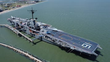 An aircraft carrier docked at a pier with a clear view of the deck and surrounding water.