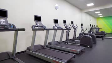 A gym with treadmills, ellipticals, and a water bottle on a bench.