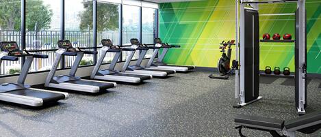 Un gimnasio moderno con cintas de correr, bicicletas estáticas y mancuernas de kettlebell.